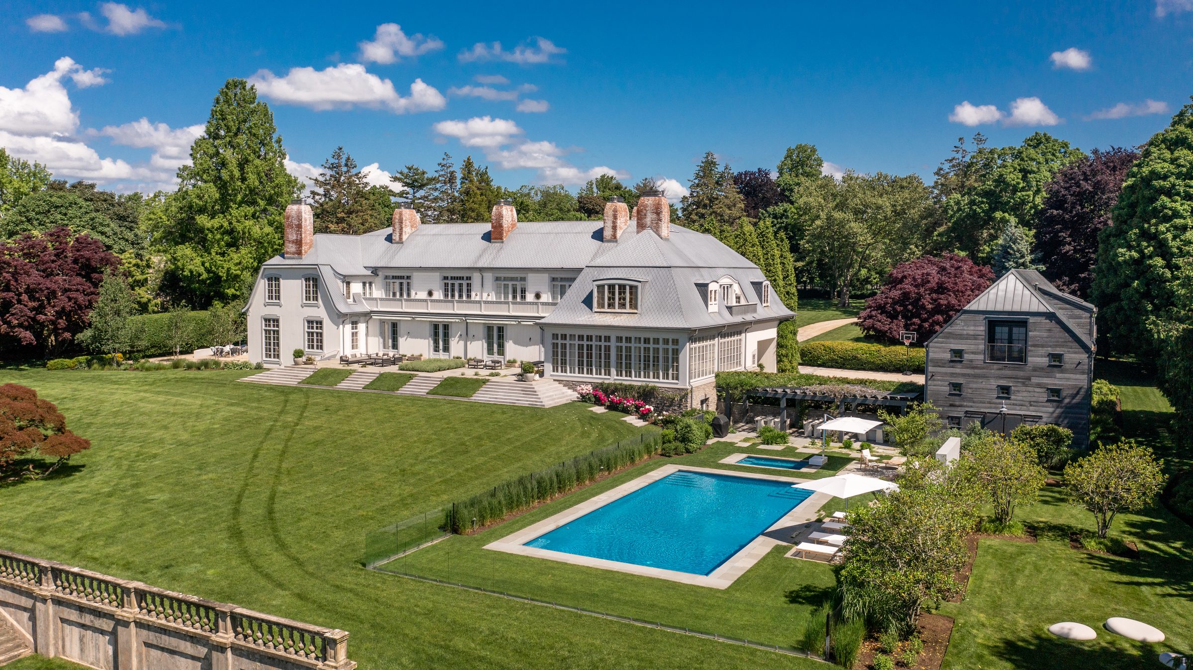 Aerial view of a white estate with a pool and manicured lawns in Fairfield, Connecticut